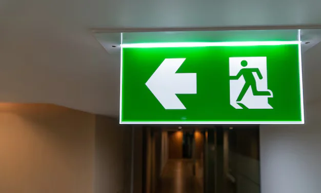 Green fire escape emergency exit sign in office interior