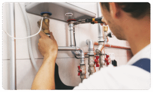 Plumber repairing boiler pipes and fittings for safe heating system maintenance